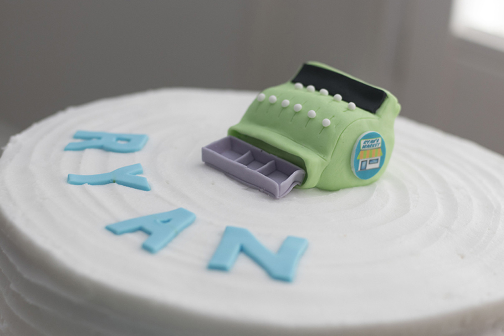 first birthday cake with green cash register on top