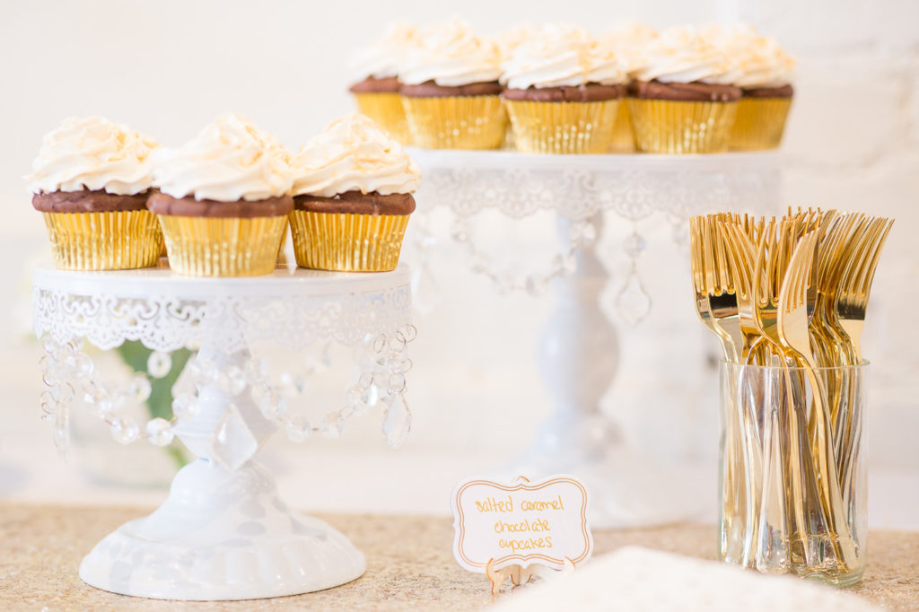 chocolate cupcakes in gold liners on white cake stands