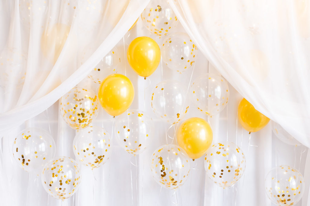 photo booth setup with gold glitter balloons and white sheer curtains