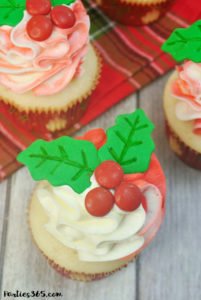 Looking for Christmas Cupcake ideas for the holidays? Our Holly Cupcake Recipe is a fancy dessert that's still easy to make! The cute fondant leaves and M&M berries really stand out on the candy cane inspired frosting. Click for the full recipe! #holidaybaking #holidayrecipes #Christmas