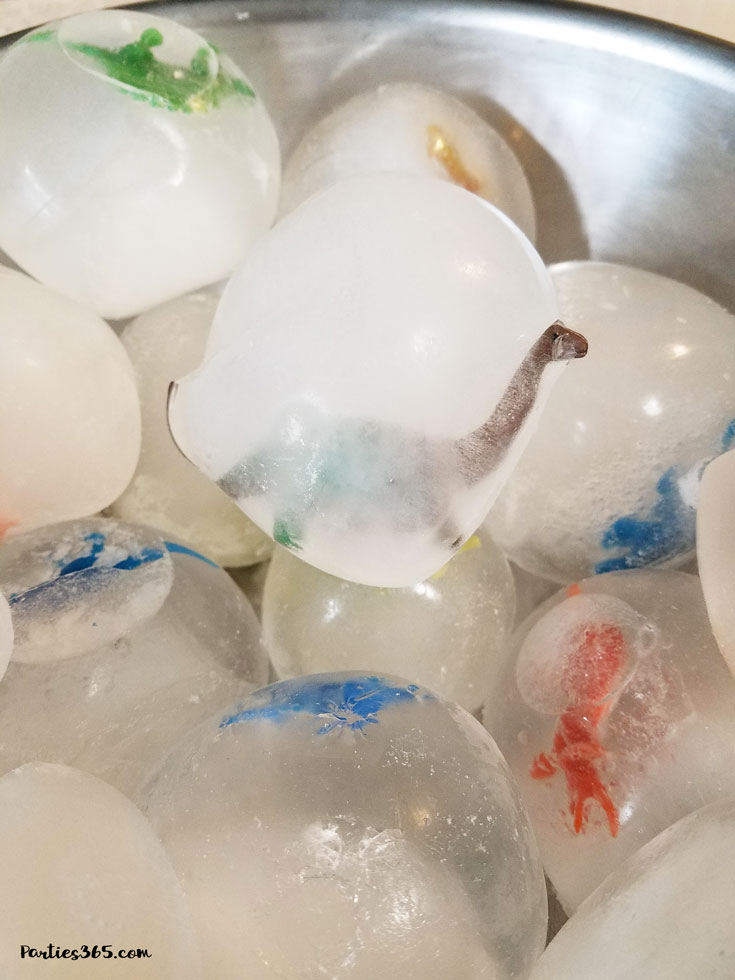 toy dinosaurs frozen in balls of ice as dinosaur eggs