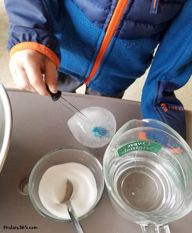 child using dropper to melt dinosaur ice egg