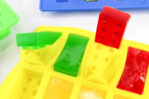 Want a fun treat for your lego themed birthday party? Let us show you how to make colorful Jello Lego blocks and figurines with this easy recipe and mold! #legos #legoparty #legofood #birthday #partyfood