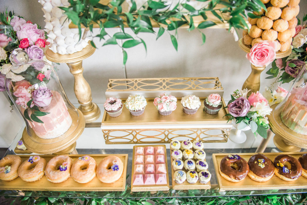 spring party dessert table with cupcakes, donuts and sweet treats