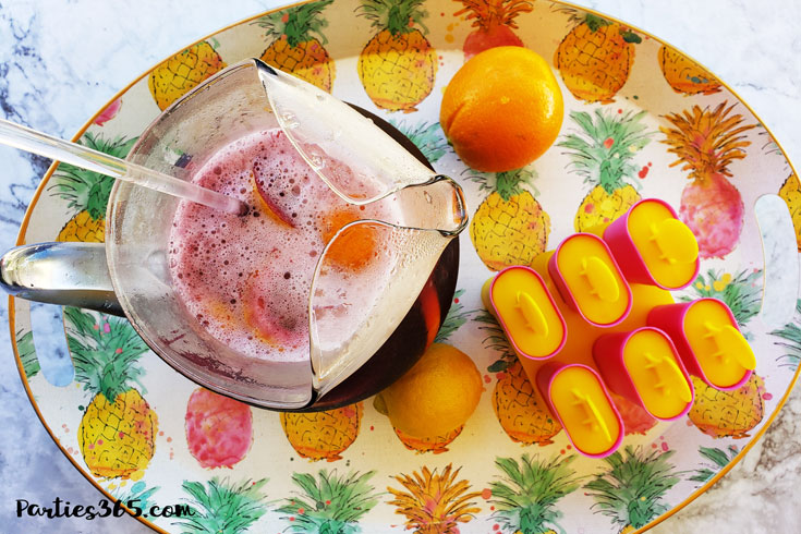 pitcher of sangria next to popsicle molds on a summer serving tray