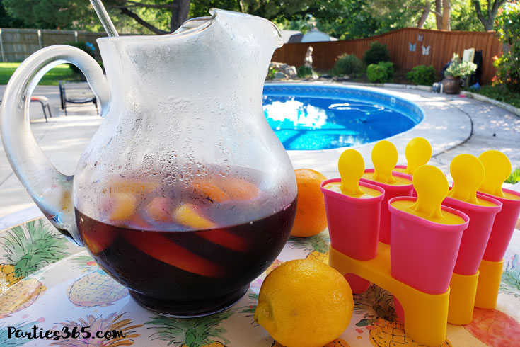 pitcher of sangria next to pink and yellow popsicle molds