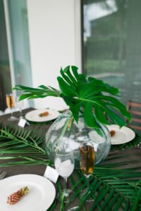 Want to set a beautiful outdoor dining table for a summer party? You'll love this simple tablescape featuring a palm leaf centerpiece and tropical decor! Click through to see all the summery tabletop decorations! #summerparty #outdoordining #tablescape #centerpiece #tropical