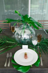 Want to set a beautiful outdoor dining table for a summer party? You'll love this simple tablescape featuring a palm leaf centerpiece and tropical decor! Click through to see all the summery tabletop decorations! #summerparty #outdoordining #tablescape #centerpiece #tropical