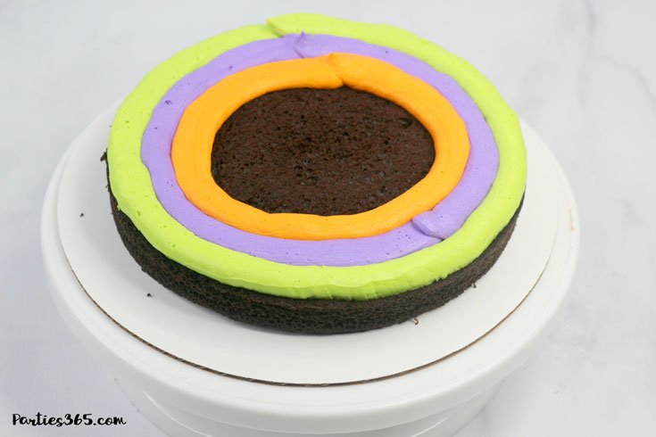 chocolate cake layer with electric green, purple and orange icing
