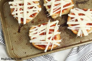 This super fun and easy Halloween Mummy Pizza recipe will be spooktacular for the kids! Whether you want to make a festive dinner for your family or something special for a Halloween party, these Mummy Pizzas are easy, quick and delicious! #Halloween #Halloweenrecipes #mummy #mummypizza #halloweenparty