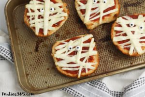This super fun and easy Halloween Mummy Pizza recipe will be spooktacular for the kids! Whether you want to make a festive dinner for your family or something special for a Halloween party, these Mummy Pizzas are easy, quick and delicious! #Halloween #Halloweenrecipes #mummy #mummypizza #halloweenparty