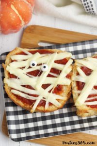 This super fun and easy Halloween Mummy Pizza recipe will be spooktacular for the kids! Whether you want to make a festive dinner for your family or something special for a Halloween party, these Mummy Pizzas are easy, quick and delicious! #Halloween #Halloweenrecipes #mummy #mummypizza #halloweenparty