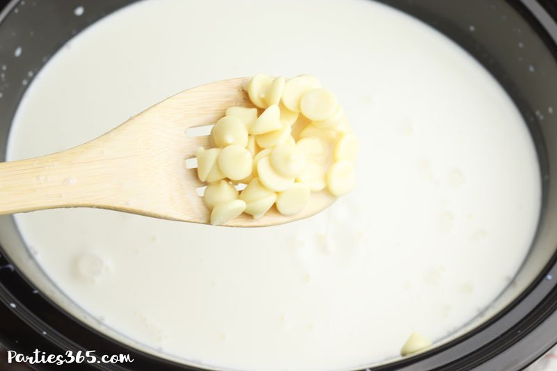 adding white chocolate chips to crock pot for hot chocolate