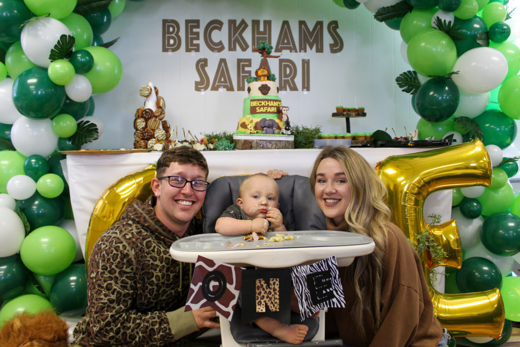 family at 1st birthday wild one safari themed birthday party in front of high chair