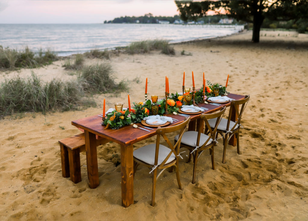summer dinner party table set in sand next to water