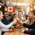 Young adults enjoying drinks at a Canadian bar with the Canadian flag in the background