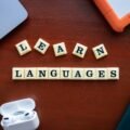 best apps for language learning — learn languages desk scene with phone, laptop, and earbuds