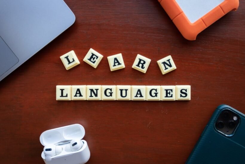 best apps for language learning — learn languages desk scene with phone, laptop, and earbuds