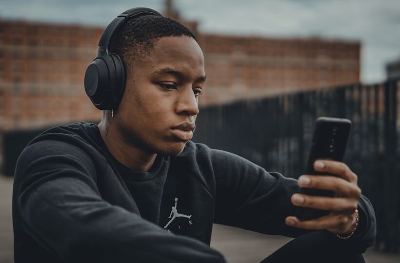 Man in headphones checking Y2Mate MP3 download apps on his Android phone outdoors