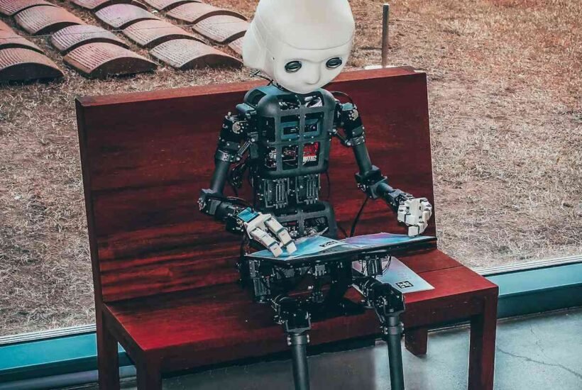 A humanoid robot sits alone on a bench reading, illustrating the AI companion experience people look for in apps like Character AI