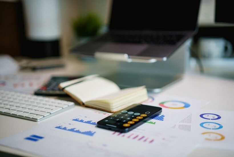 Apps like Empower compared on a desk with a phone calculator, budget printouts, and spending charts
