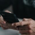Loan apps like Dave compared on a phone next to a handwritten budget with bank balances and due dates