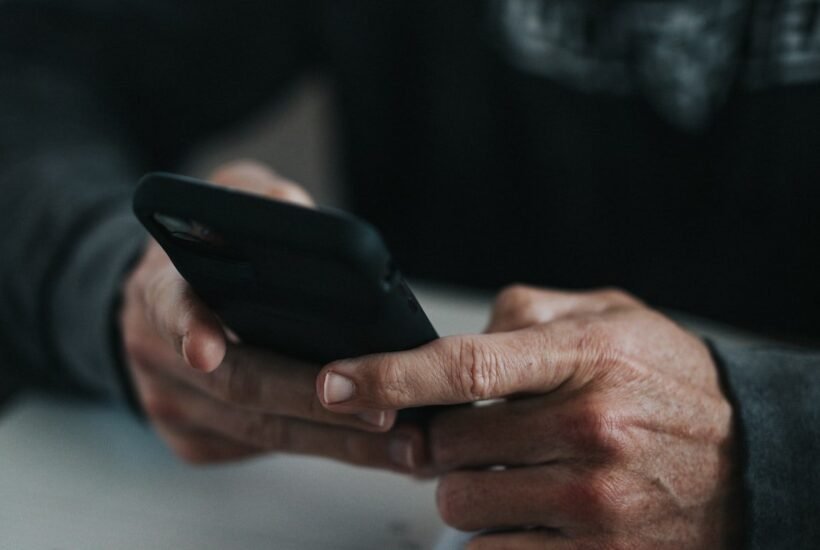 Loan apps like Dave compared on a phone next to a handwritten budget with bank balances and due dates