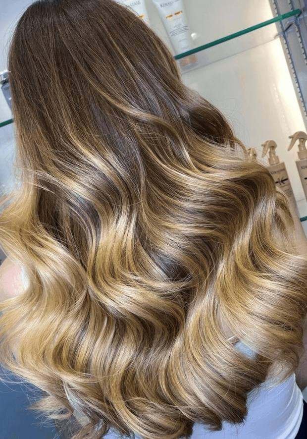 Long wavy hair from behind, brown at the root melting into golden-blonde balayage ends, a Rush Hair & Beauty photo